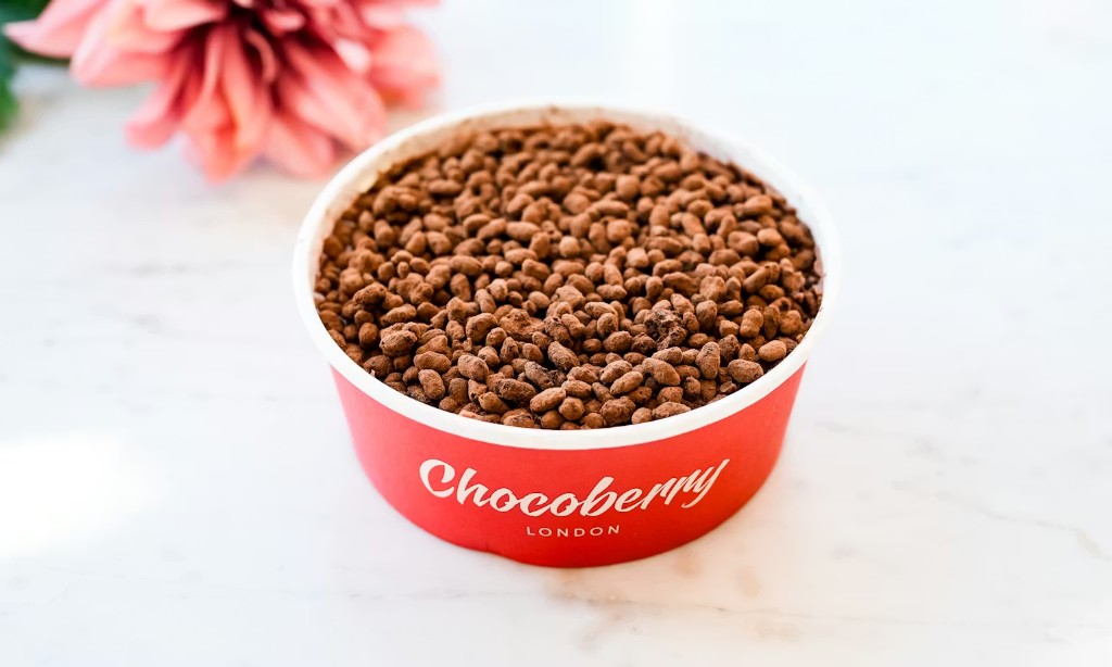 Red dessert cup with cocoa-dusted treats on marble