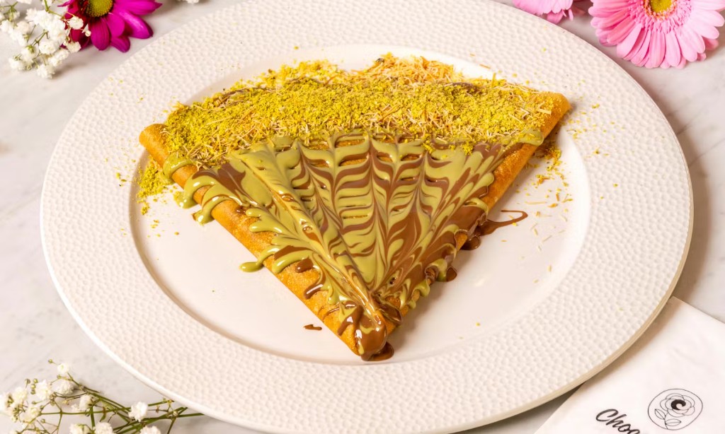 Folded crepe with pistachio and chocolate drizzle on marble